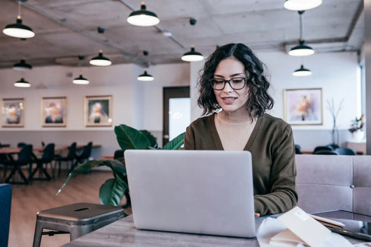 Small business owner sitting down at her laptop writing a blog.