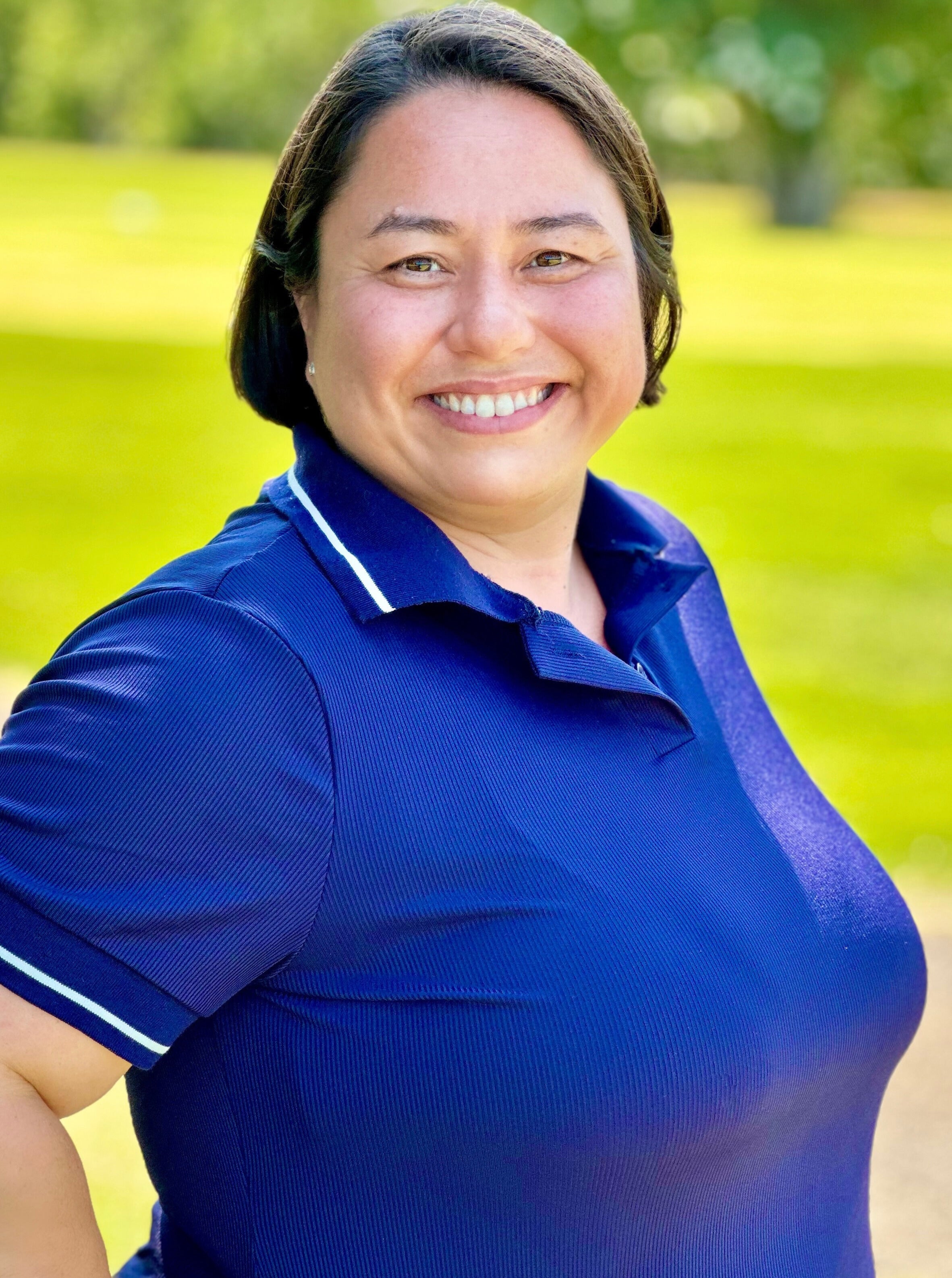 Donna YORK wearing a blue polo shirt with a blurred green background.